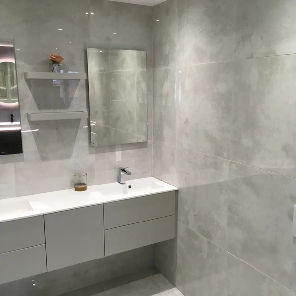 Luxor Grey gloss porcelain tile used on bathroom walls, featuring a polished marble-effect finish above a double vanity.