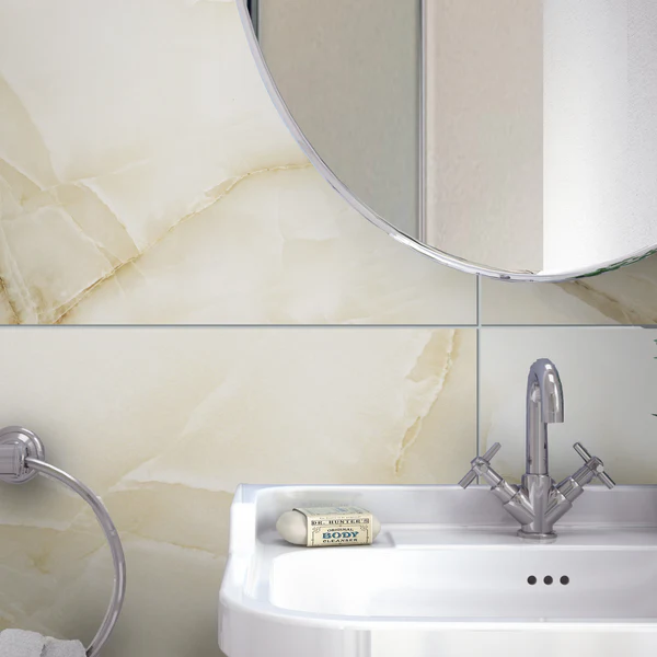 Onyx Oyster gloss wall tiles installed in a luxurious bathroom above a white sink with a chrome faucet and round mirror.