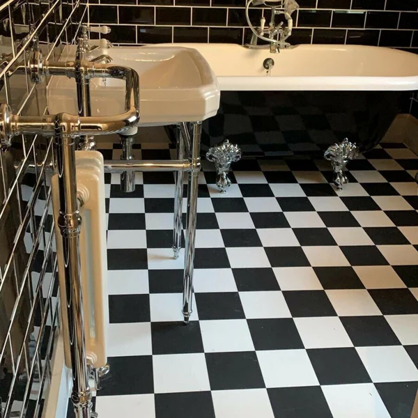 Black and white Ral floor tiles in a chic, classic bathroom with a freestanding clawfoot tub and subway wall tiles.