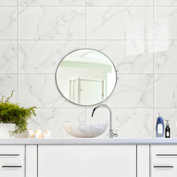 Bathroom vanity wall with glossy Steady Marble Sugar Wall Tile, a white marble-effect with subtle grey veining, and a round mirror.