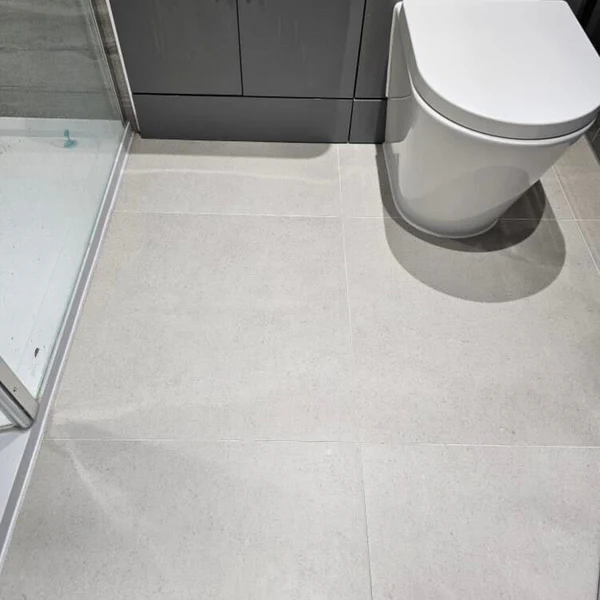 Bathroom floor close-up with Grey Stonetech Wall & Floor Tile, a light, subtle stone-look finish next to a white toilet and shower.