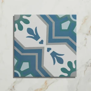 Cabana Porcelain Algarve 20x20cm tile close-up with a blue, green, and grey floral geometric quarter-pattern on a light marble background.