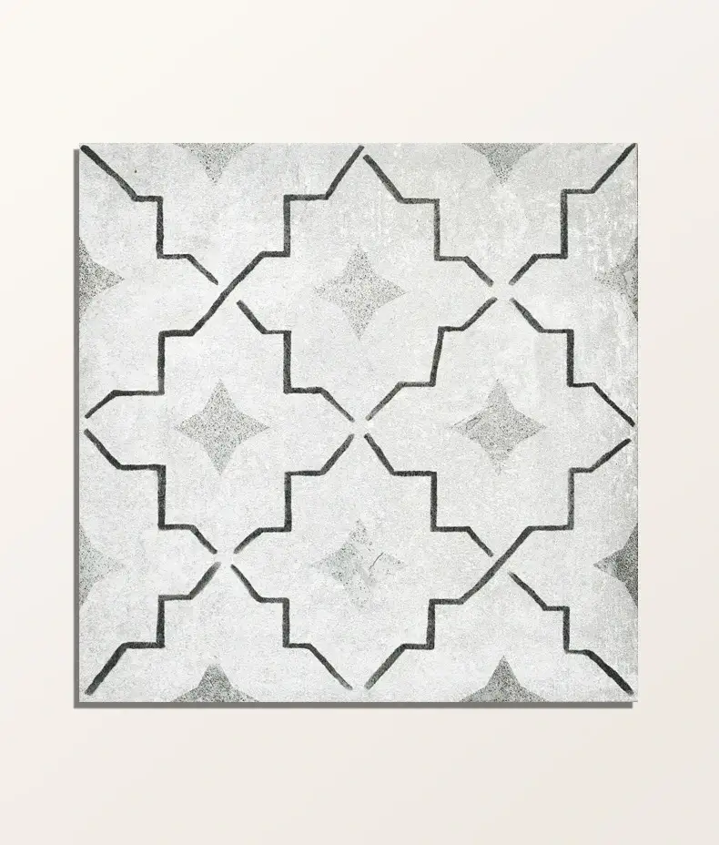 Cuba Porcelain Como 20x20cm tile close-up with a grey and black quatrefoil geometric pattern on a distressed, light grey background.