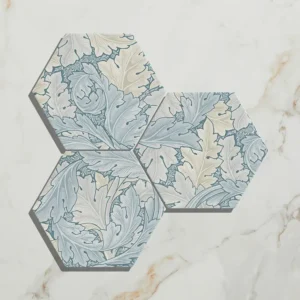 Folly Porcelain Lake Matt 20x23cm hexagonal tiles (three pieces) with a detailed blue, grey, and white leaf/acanthus pattern on white marble.