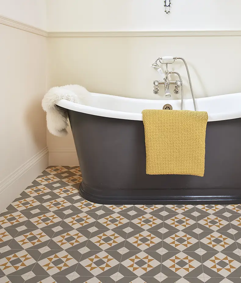 PORTARE Brompton Euston 20x20cm floor tiles with a grey, white, and ochre geometric star pattern next to a black freestanding bathtub.