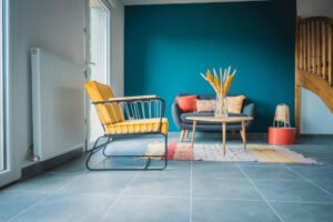 Modern living room with blue floor tiles, a yellow armchair, and a teal feature wall, showcasing a professional spring home tiling project.