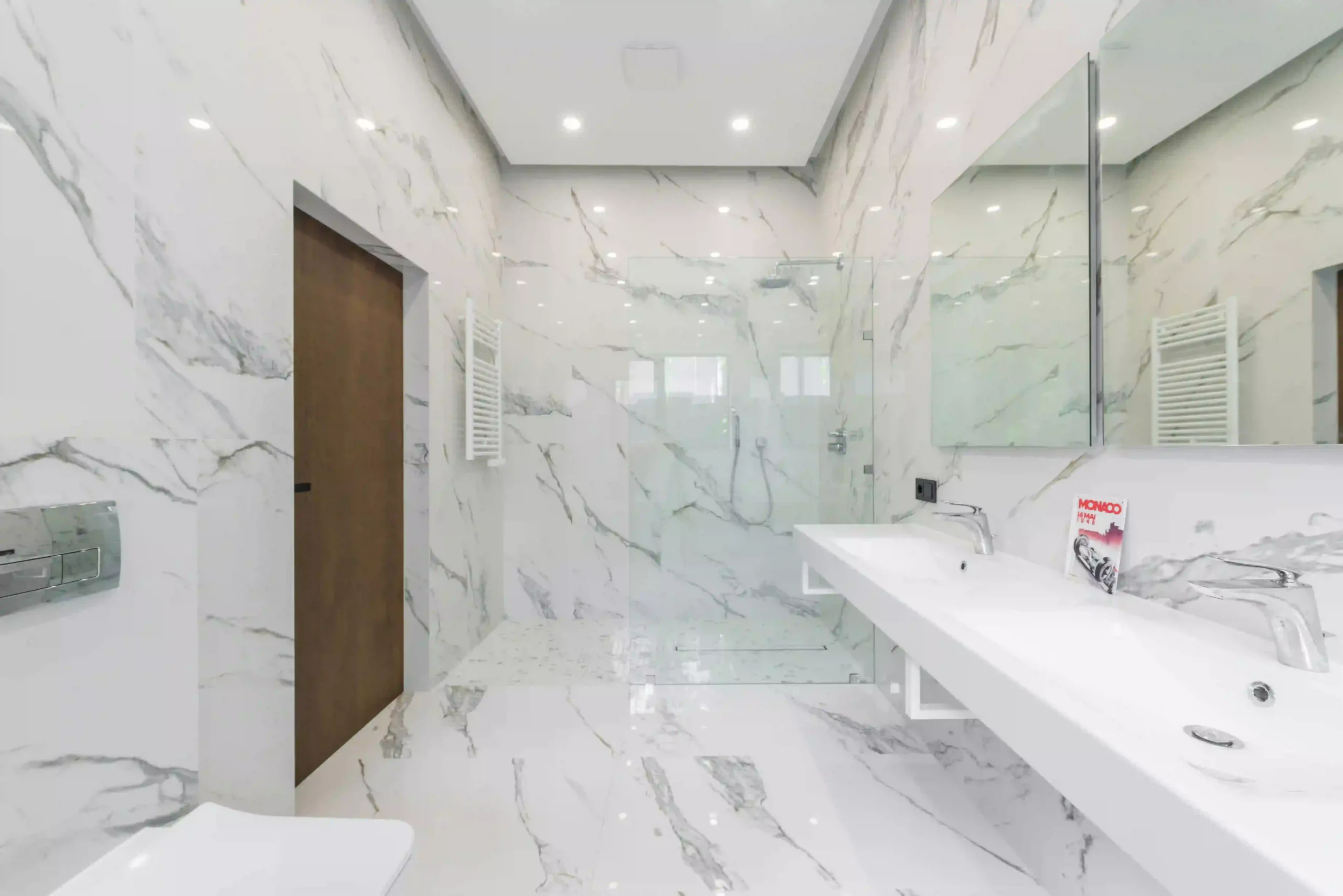 Modern UK bathroom featuring large format marble-effect porcelain tiles on the walls and floor with a seamless finish.